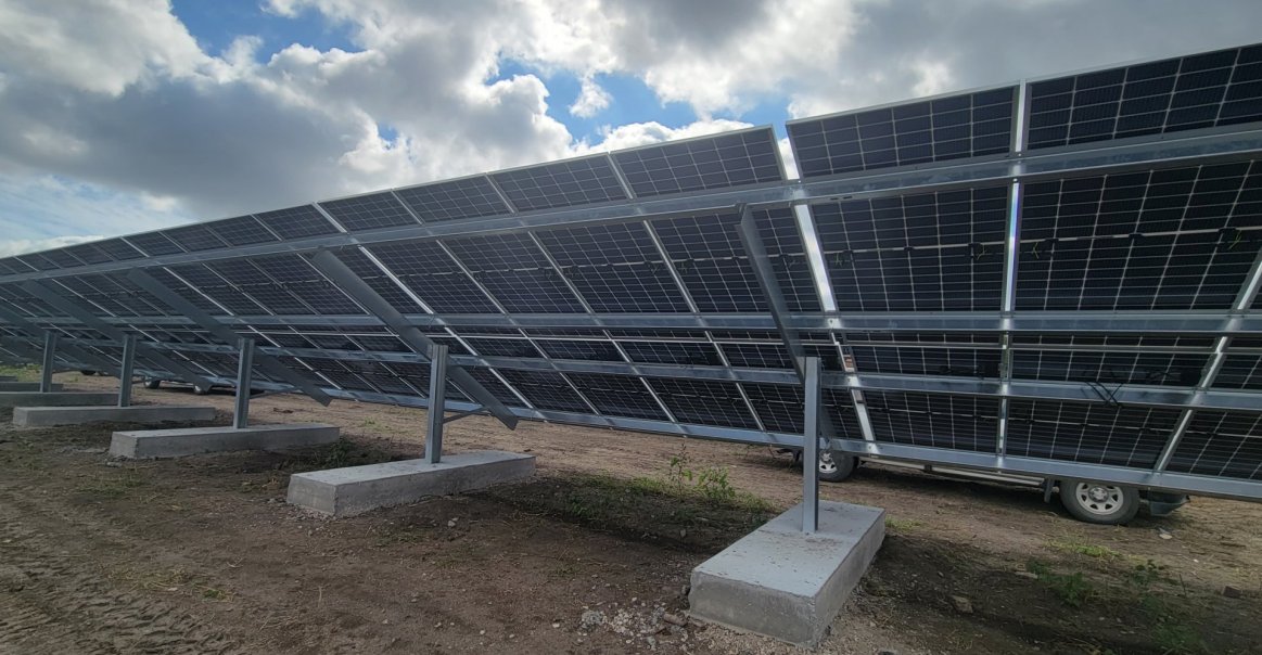 View of backsheets in solar panel ground mount array commercial project. Due to being a reclaimed landfill ground could not be disturbed more ground cap - Installation was 30 degree fixed tilt ground array with ballast above ground undisturbing the land - challenge to layout array in given dimensions and soil depth Otherwise unusable ground being utilized to produce electricity feeding City of Des Moines' Green house and Animal Control Facilities saving tax payer dollars 2-3 sentences on their experience partnering with Greentech Renewables. Greentech coordinated all engineering drawing from racking manufacturer helping to fulfill the City of Des Moines requirements Greentech coordinated logistics for product delivery during the installation process with minimal laydown yard Joshua Clark was our key pint of contact for final BOM and system development making the process seamless View of backsheets in solar panel ground mount array commercial project.